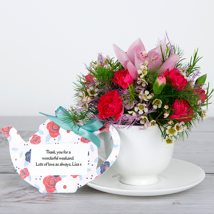 Cymbidium Orchids and Pink Spray Carnations with White Wax Flowers and Green Tree Fern in Bone China Teacup image